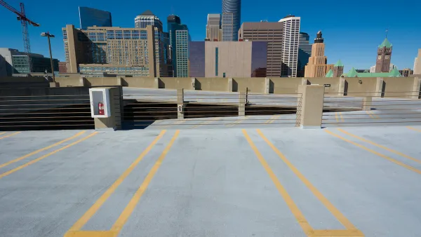 Empty parking spots on top floor of multistory garage with Minneapolis skyline in background.