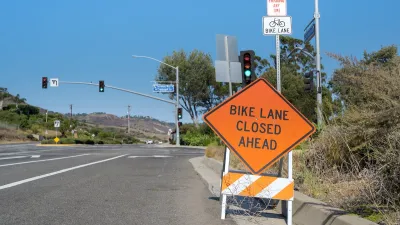 Orange "Bike Lane Closed Ahead" sign on a-frame in roadway.