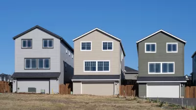 Three new single-family homes in a row on a lot with no trees.