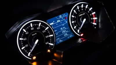 Close-up on car dashboard with odometer and speedometer at night.