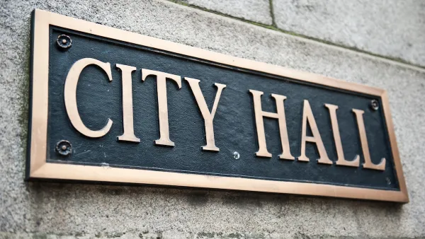 Close-up of "City Hall" plaque on building with gold lettering on black.