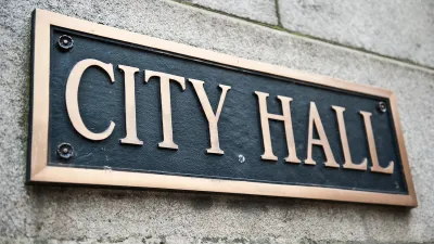 Close-up of "City Hall" plaque on building with gold lettering on black.