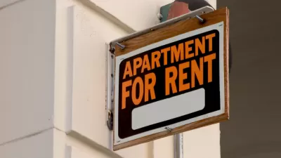Close-up of black, white, and orange APARTMENT FOR RENT sign on building.