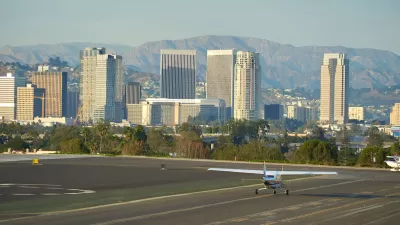 Small plane on runway at Santa Monica airport with high-rise buildings in background.