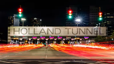 View of large HOLLAND TUNNEL sign tollbooths with blurred red taillights in foreground