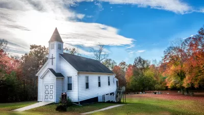 Small white wooden church in rural setting.