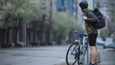 An adult man, stopped on a Seattle, Washington street corner, preparing for a rainy morning bike commute.