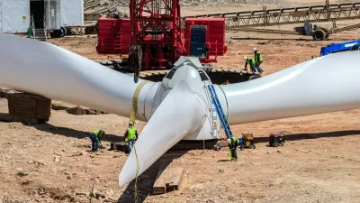 White wind turbine sitting on ground at wind farm construction site.