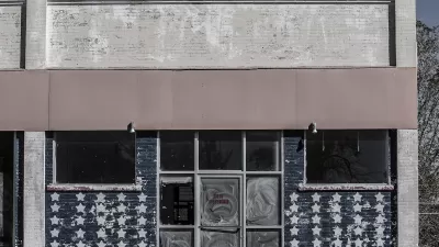 Faded image of vacant storefront in rural area with American flag stars painteind on windows.