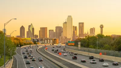 View of Dallas city skyline with moderately busy freeway in foreground at twilight.