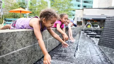 Young girls dipping their hands in an outdoor decorative water fountain