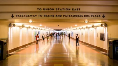 View looking down indoor concourse at Los Angeles Union Station with “To Union Station East” and “Passageway to Trains and Patsaouras Bus Plaza” signs.