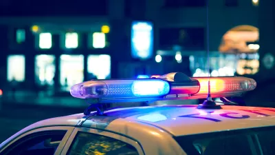 Nighttime view of blue and red lights on top of a white police car.