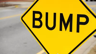 Close-up on yellow sign with black 'BUMP' letters indicating speed bump ahead.