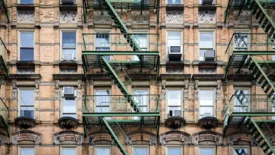 Brick New York City apartment building exterior with fire escape stairs and AC window units.