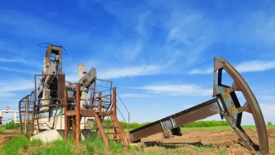 Defunct oil well disassembled in green field.