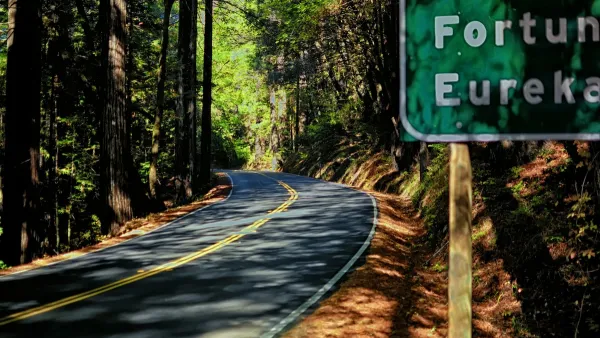 Highway 101 winding through redwood trees with road sign for Eureka, CA partially visible in top right.