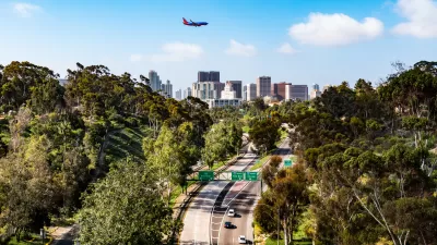 An airplane flies over the Cabrillo Freeway (State Route 163) as it passes through Balboa Park and into the downtown area of San Diego, California.