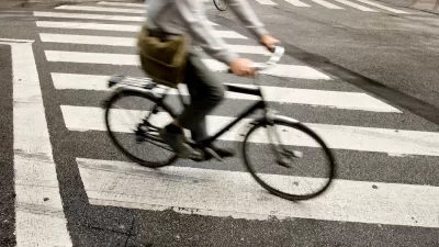 Person on bike riding across zebra crosswalk in city.