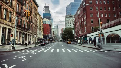 New York City street with painted bike lane and crosswalk flanked by brick buildings.