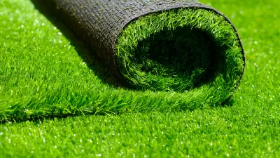 Close-up of roll of green artificial turf laying on more artificial turf.