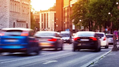 Blurred cars driving down road with European road signs visible.