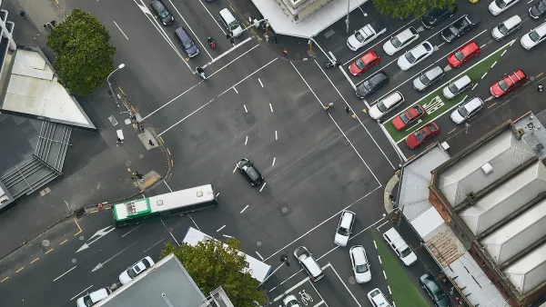 Bird's eye view of busy urban intersection with bus lanes, traffic, and pedestrians.