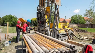 Workers next to excavator digging a geothermal well.