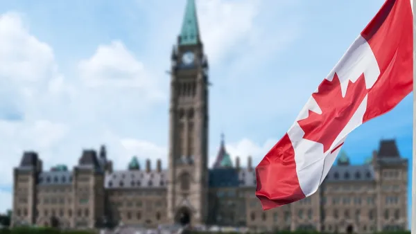 Canadian flag in foreground with blurred Canadian Parliament building in background in Ottawa, Ontario, Canada.