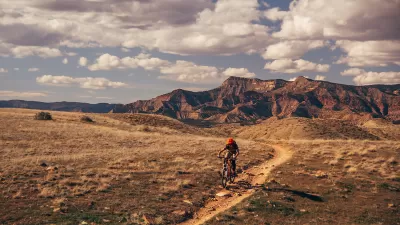 Person on mountain bike biking on trail in Colorado with mountains in background