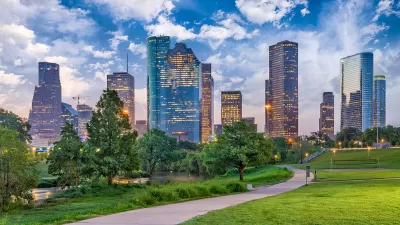 Green lawn and walkway in downtonw Houston park with skyline in background.