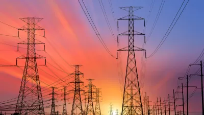 High voltage power line towers sillhouetted against colorful sunset sky.