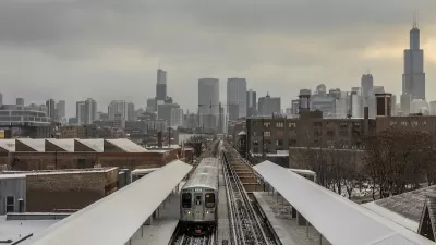Train on elevated track on snowy city landscape with Chicago skyline in background.