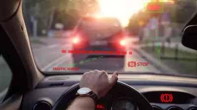 Close-up of car steering wheel and dashboard with driver's hand on steering wheel and illustration of automatic braking system on windshield with 'STOP' graphic.