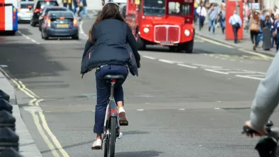 Woman rides a bike on street in London, UK.