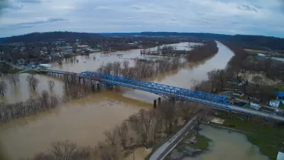 Aerial view of a blue bridge over a wide, flooded river in Kentucky.