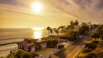 View of oceanfront homes in Malibu, California against golden afternoon sky