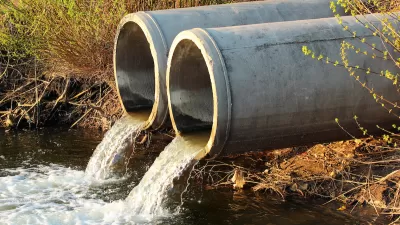 Two concrete pipes discharging dirty water into river.