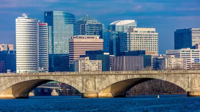 Washington D.C. office buildings with river and stone arched bridge in foreground.