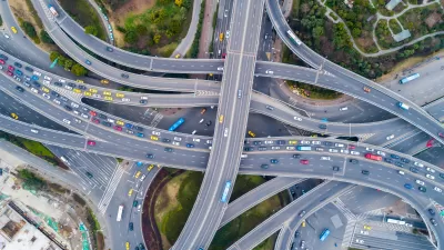 Aerial view of layered overpasses and highway intersections filled with cars.
