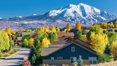 Residential neighborhood in Colorado with fall foliage and snowy mountains in background.