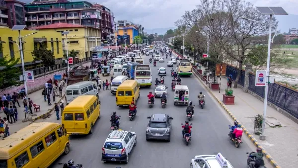 Street scene in Kathmandu, Nepal with yellow minibuses and other traffic.