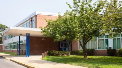 Brick school building with mid-sized tree on front lawn.