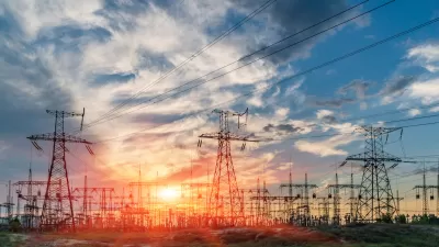 View of power towers at electric distribution substation against colorful sunset sky.