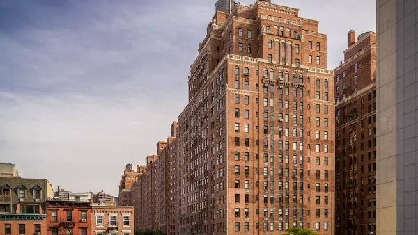 Tall red brick public housing building in New York City surrounded by shorter apartment buildings.
