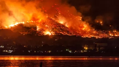 Wildfire burning at night on hillsides next to Lake Elsinore, California.