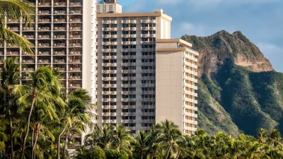 High-rise apartment buildings in Waikiki, Hawaii with steep green mountains in background.