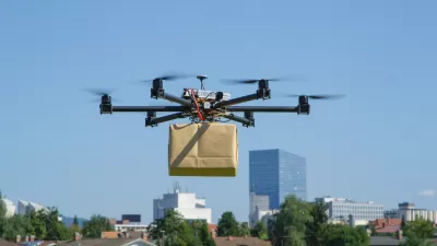 Delivery drone holding a brown paper wrapped box hoveringin air with city in background.