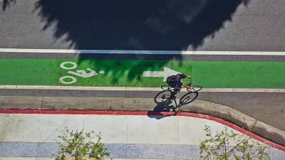 Bird's eye view of green painted bike lane with one cyclist.