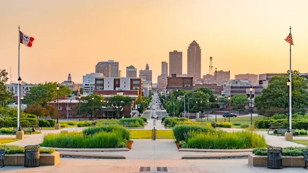 Des Moines, Iowa skyline viewed from a plaza with two flags on either side at dusk.
